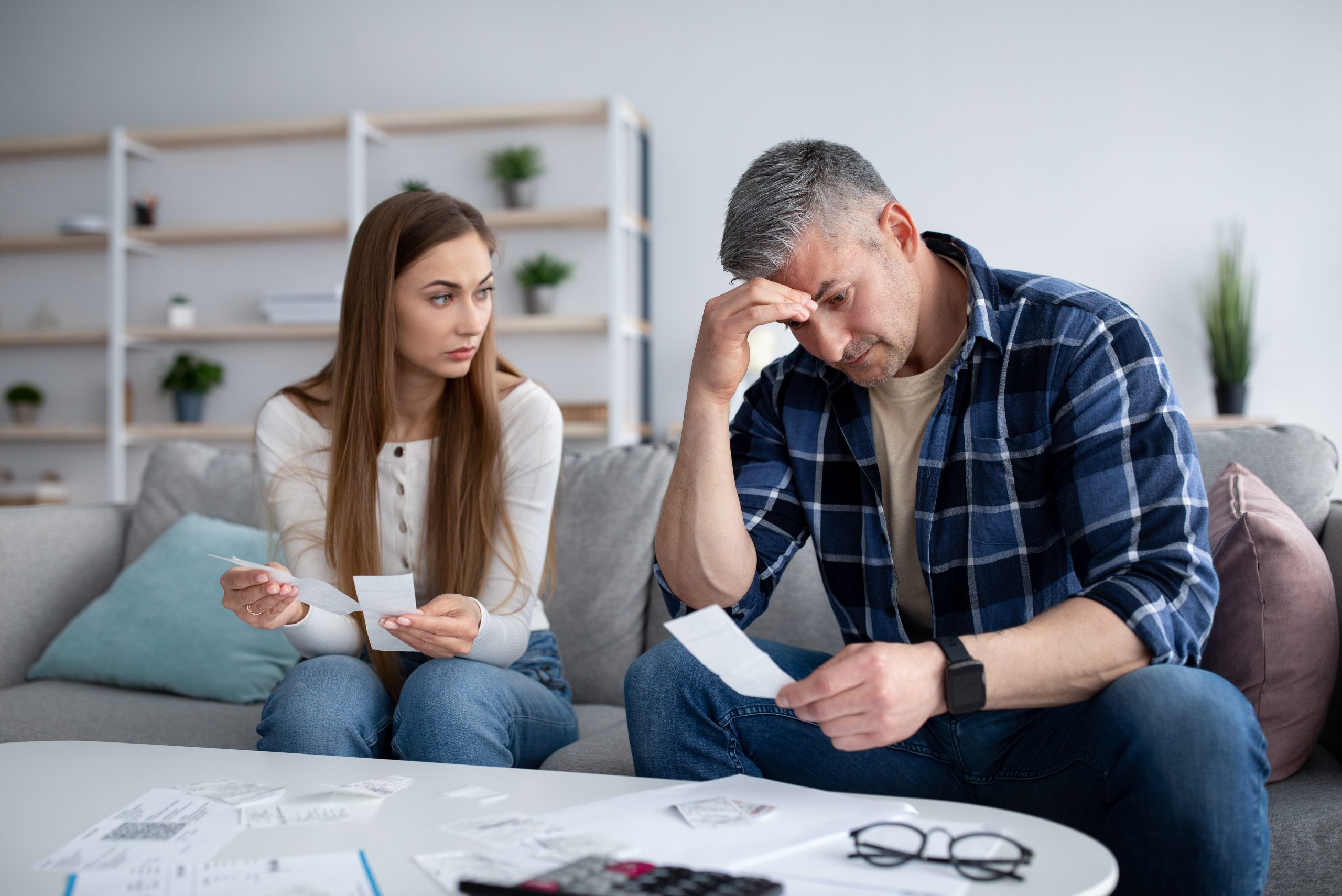 Serious mature man and his wife calculating family budget or taxes, checking bills and expenses, having debts at home