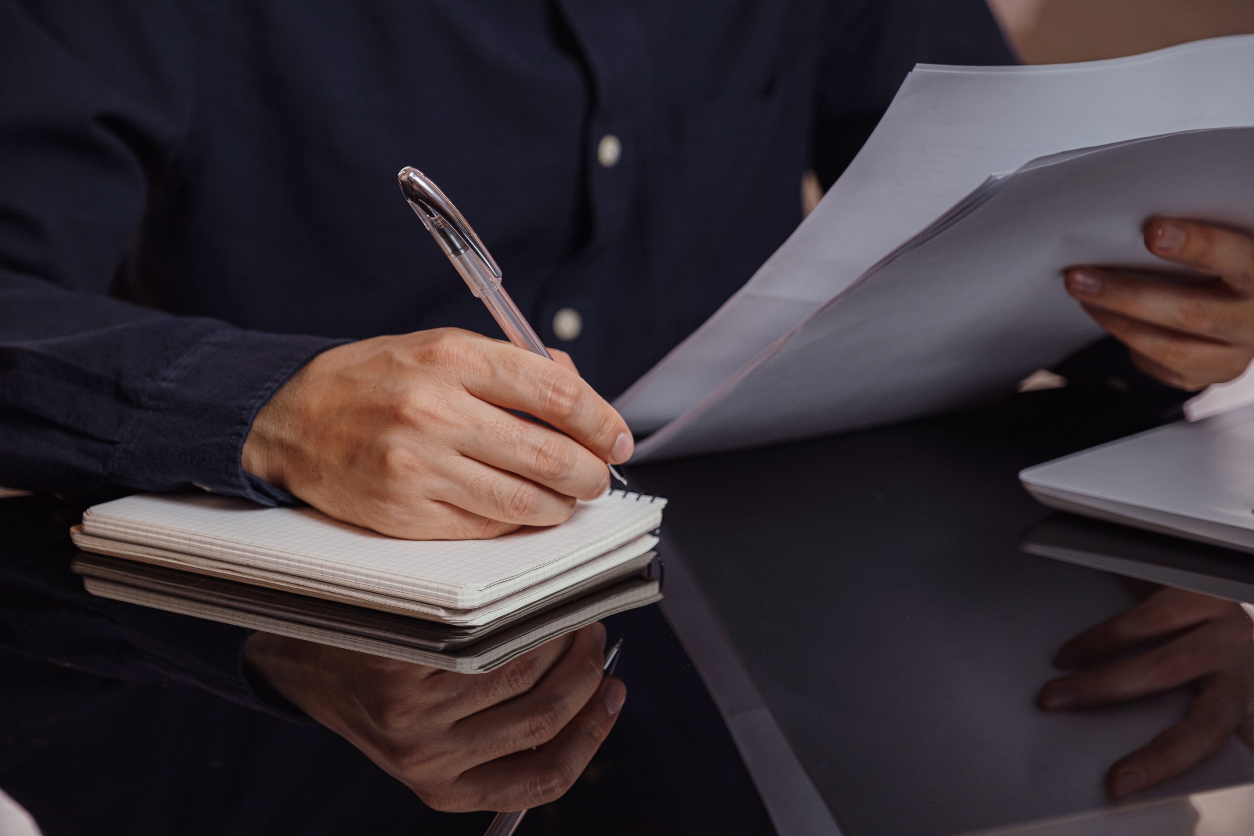 Entrepreneur works with a laptop and keeps a document in a home office