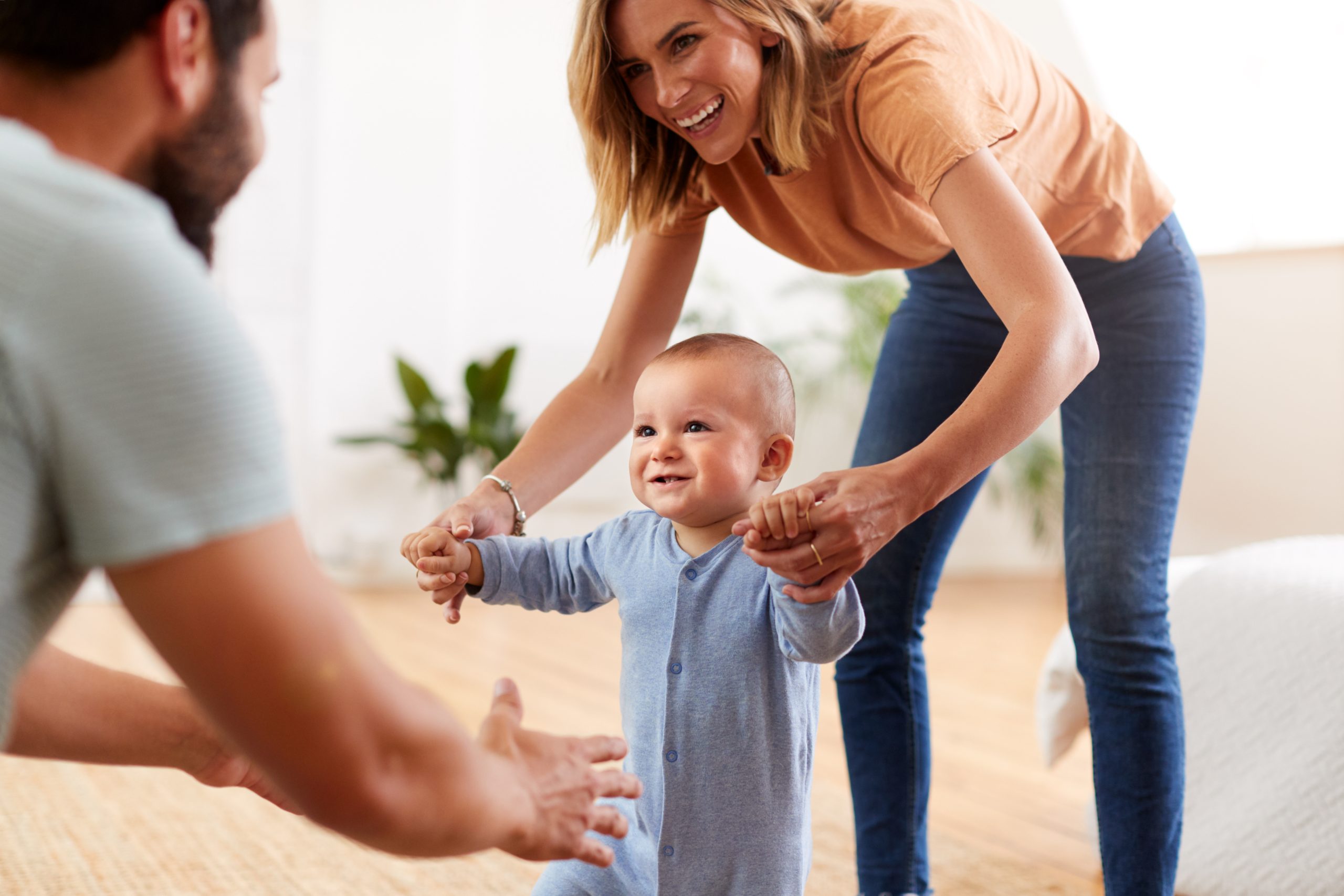 Parents At Home Encouraging Baby Son To Take First Steps