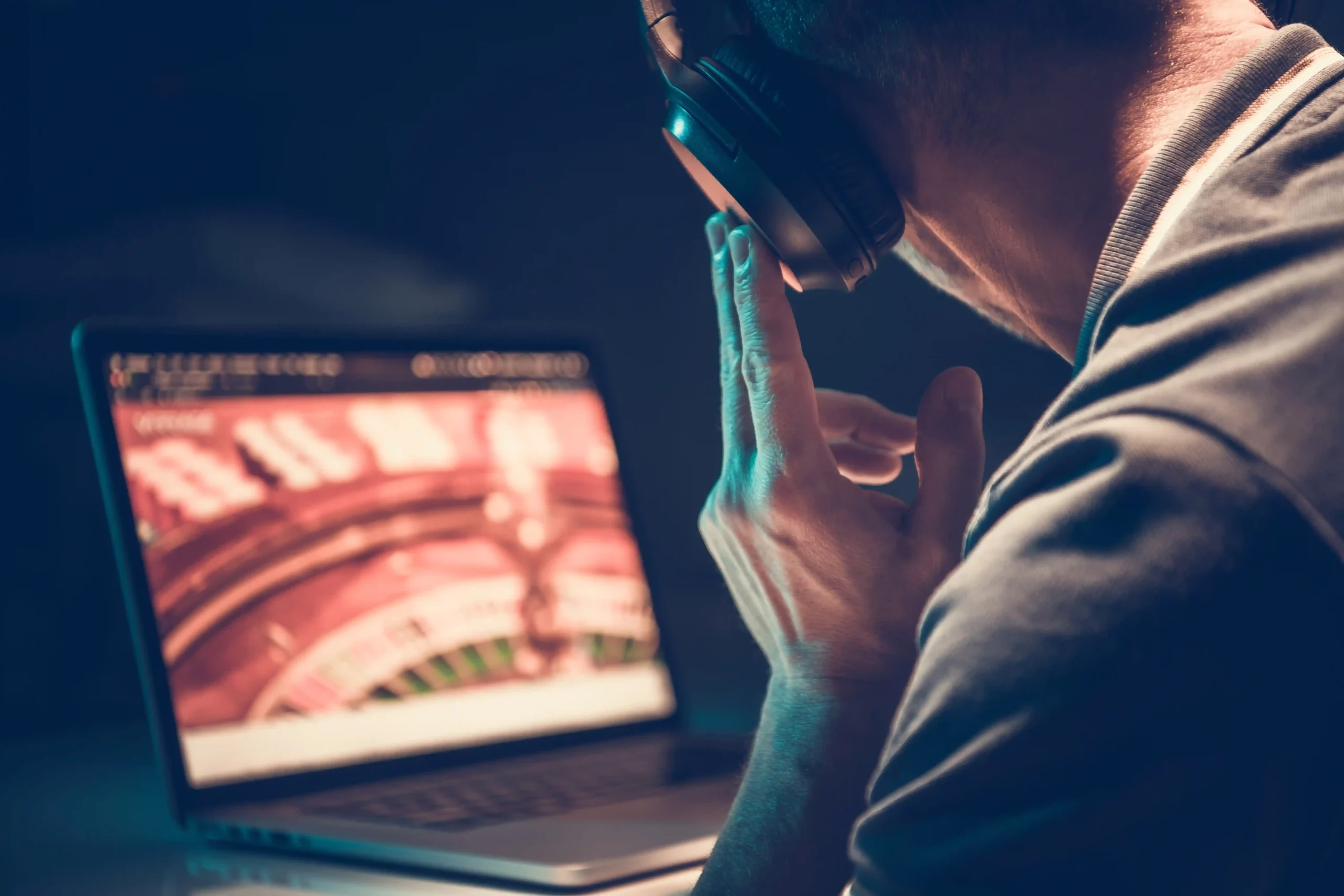 Nielegalny hazard online Mężczyzna w słuchawkach przed laptopem z uruchomioną grą hazardową online