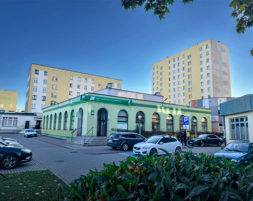Budynek siedziby Banku Spółdzielczego w Suwałkach przy ul. Utrata 4, otoczony samochodami i budynkami mieszkalnymi